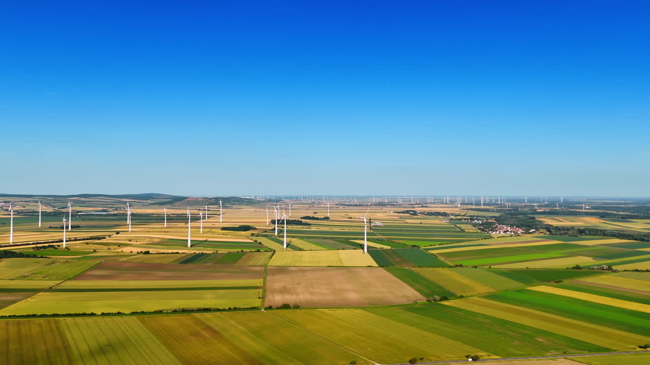 Multiple wind turbines installed in the vast fields. Green energy production. Aerial perspective.