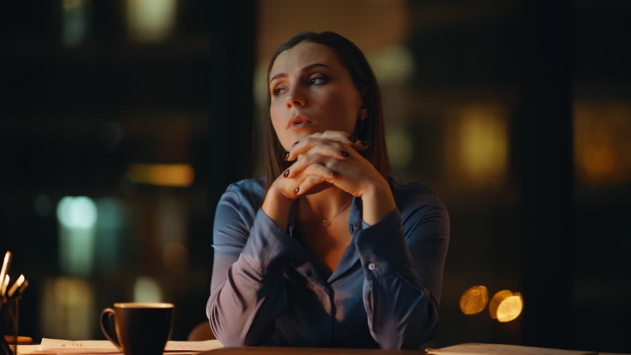 Exhausted office worker feeling burnout sitting desk in dark workspace closeup