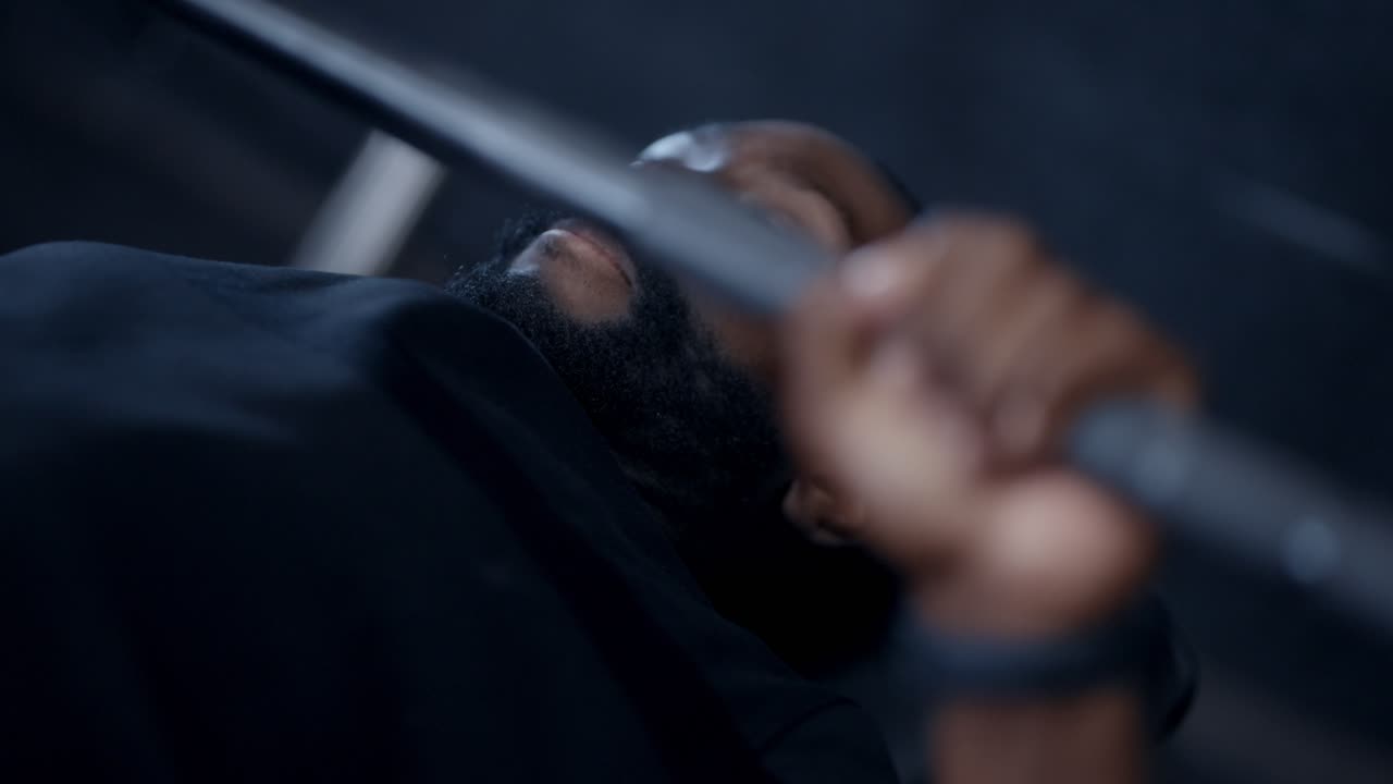 A black man bench-pressing weight in the gym