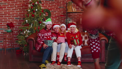 Man-sets-timer-on-mobile-phone-taking-multigenerational-family-selfie-portrait-celebrating-Christmas