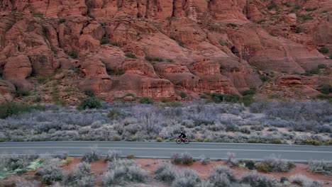Hombre-Andar-En-Bicicleta-En-Snow-Canyon-Drive-Frente-Al-Parque-Estatal-Snow-Canyon-En-Utah,-Ee.uu.