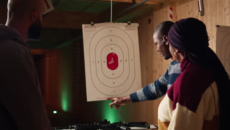 instructor de galería de tiro explicando el sistema de puntuación de bullseye a los clientes