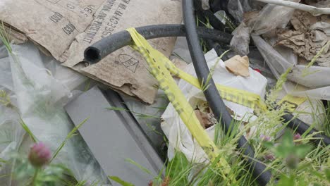 pile of garbage with caution tape and weeds