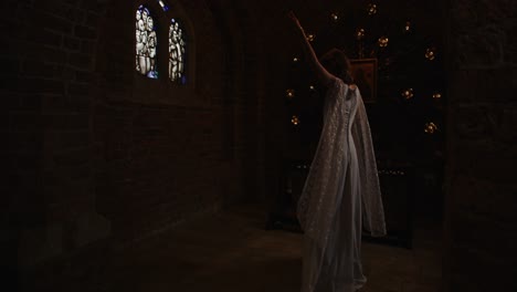 wide dolly of a woman in a beautiful long dress dancing in a small chapel in slow motion