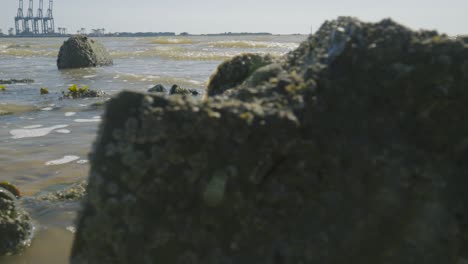 Nahaufnahme:-Wellen-Schlagen-Auf-Felsen,-Im-Hintergrund-Hafen,-Harwich