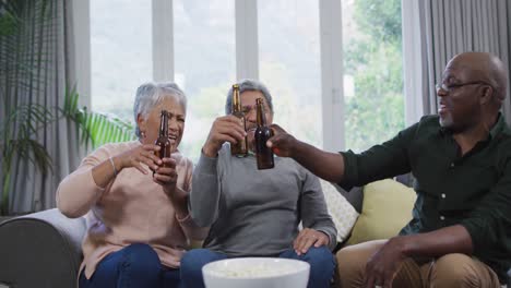 Happy-mixed-race-senior-couple-and-african-american-friend-drinking-beer-and-having-fun