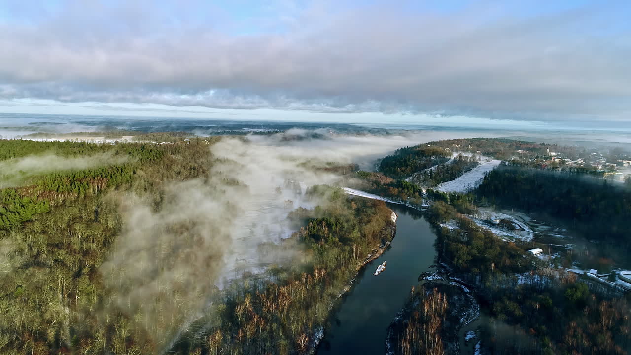 Letlands vinterlandskab med sne indhyllet i tåge langs flod og skov