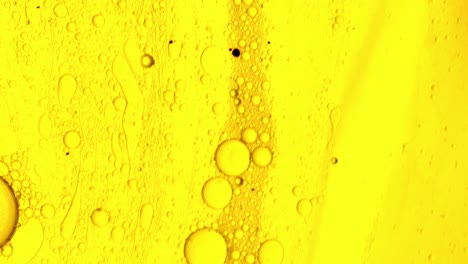 yellow oily gel that flows over a stain-like surface with bubbles of oil