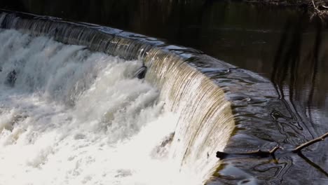 Water-running-down-stone-stepped-waterfall-surrounded-by-trees-and-greenery-5