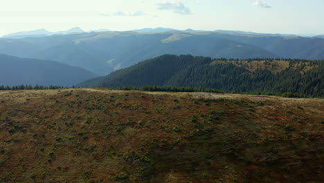 Stunning-green-mountain-road-summer-season-against-big-beautiful-rocky-peaks