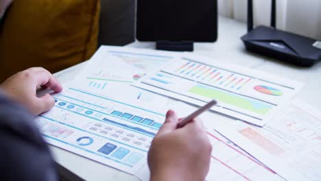 Close-up-of-a-dashboard-chart-and-hands-working-on-statistical-and-analytical-data