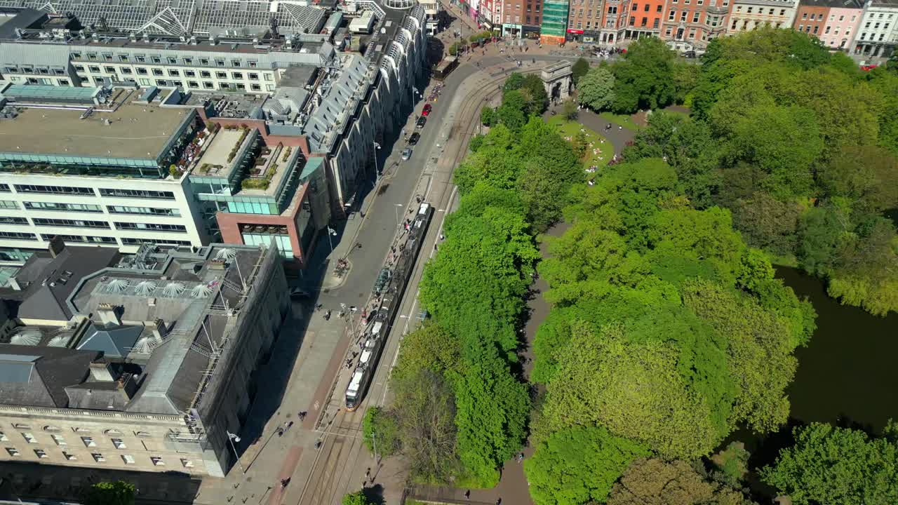 Wide, rising aerial video of the Luas Tram System operating in Dublin City Centre, County Leinster, Ireland, on a bright and sunny day. Filmed in 4K, 60FPS and with Rec709 color.