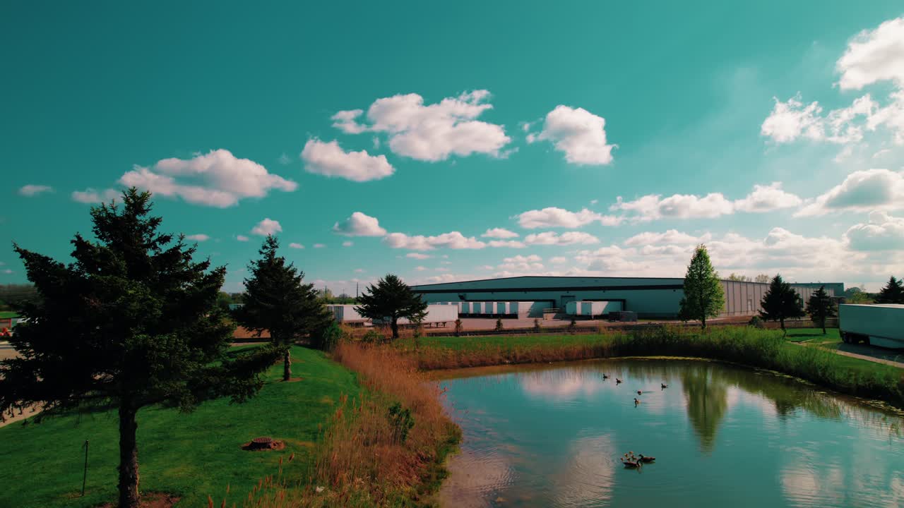 Semi trailers docked at a serene North Wisconsin logistics hub, featuring reflections on a scenic pond under a sunny sky.