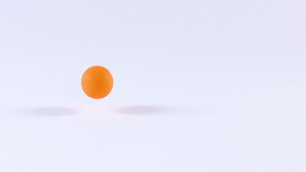 An orange ball repeatedly bounces on a smooth white surface, showcasing dynamic motion and rhythm.