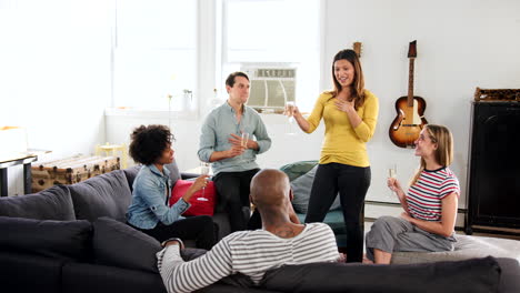 Woman-standing-to-make-a-toast-with-friends-at-an-apartment