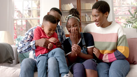 Portrait-of-happy-african-american-parents,-son-and-daughter-sitting-on-sofa-in-house,-slow-motion