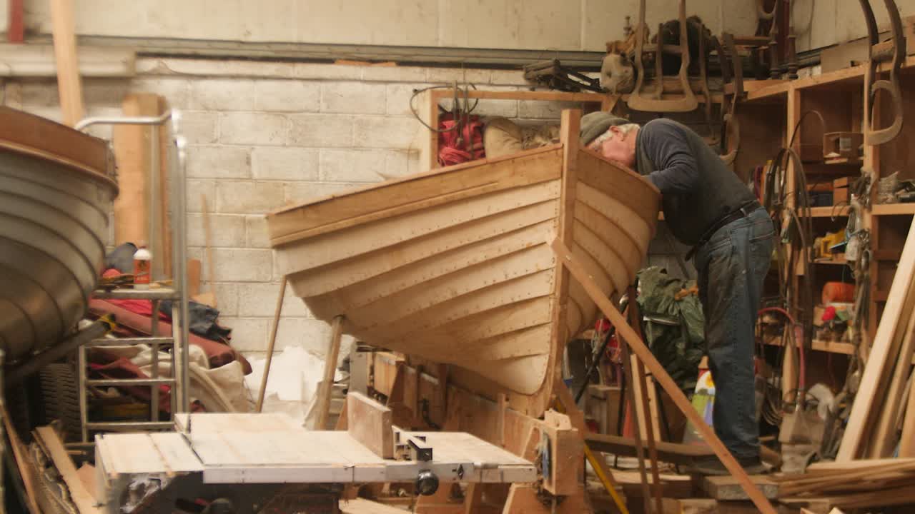 Boatbuilder working on lapstrake dinghy, punt