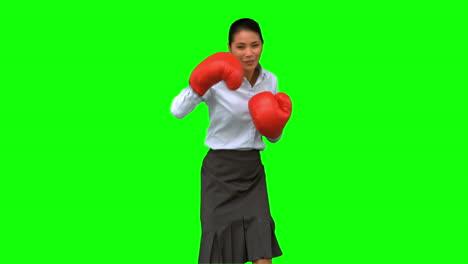 mujer de negocios con guantes de boxeo y golpeando en la pantalla verde