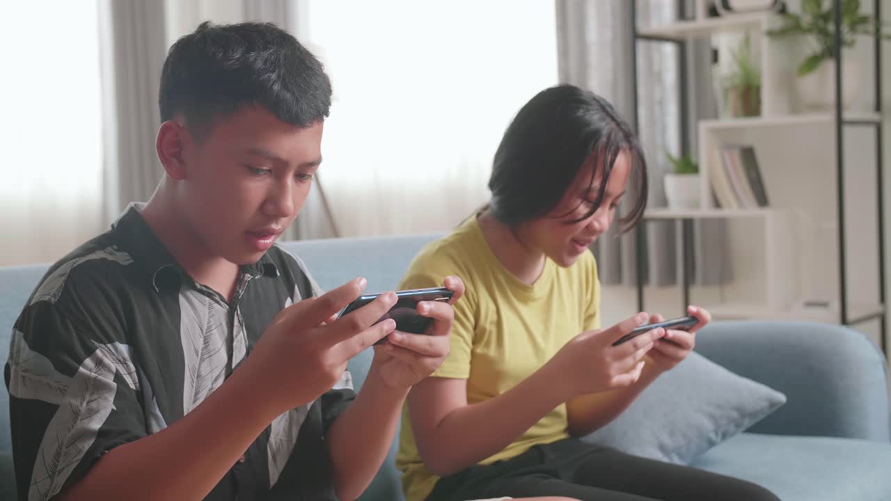 兄弟姉妹が携帯電話でゲームをしている。
