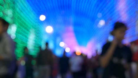 people walking street at night background, tunnel of blurred colorful bokeh light defocused background and textured for christmas