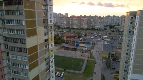 aerial view between old soviet made apartment buildings, revealing a soccer field, in a indigent slum neighborhood of kyiv, during sunset, in kiev, ukraine - rising, drone shot