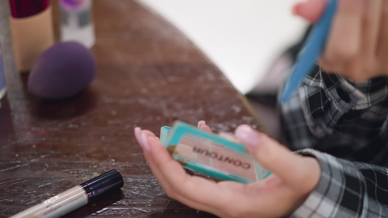 vista de primer plano de una mujer usando delicadamente un pincel de maquillaje suave para aplicar polvo en la cara, rutina de belleza en progreso con paleta de contornos y herramientas de belleza, capturando elegancia y precisión en el cuidado personal