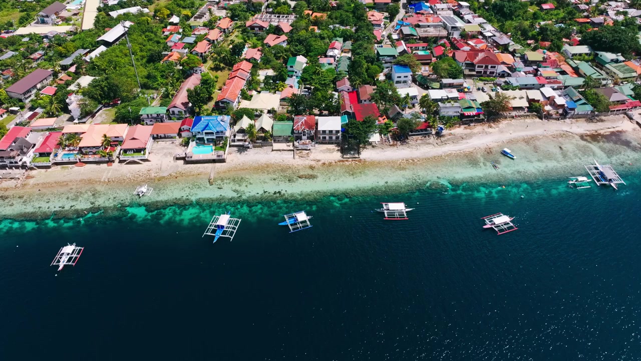 Drone terbang di atas garis pantai dan perahu di Pantai Panagsama, Moalboal, Cebu, Filipina.