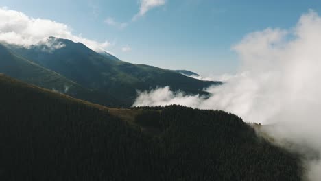 dense clouds rising from mountain large forests, sunny day with blue skies, aerial view