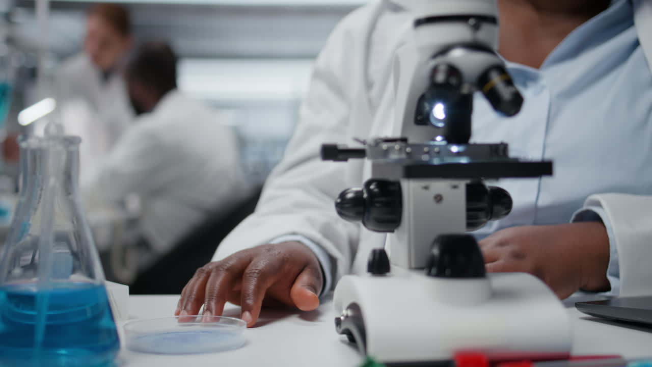 Close up of microscopist studying genetic tissue sample on petri dish