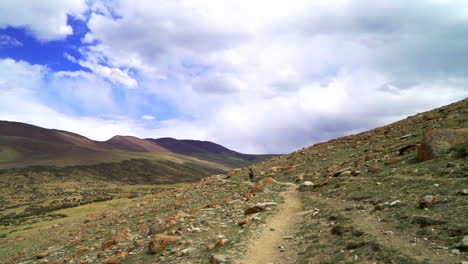 point of view shot as walking on a mountain trail, road behind another hiker