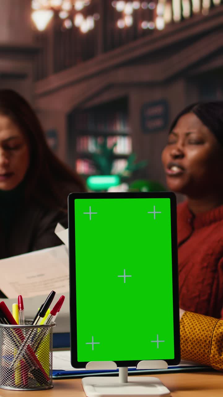 Vertical Video Mature colleagues team review paperwork next to chroma key mockup
