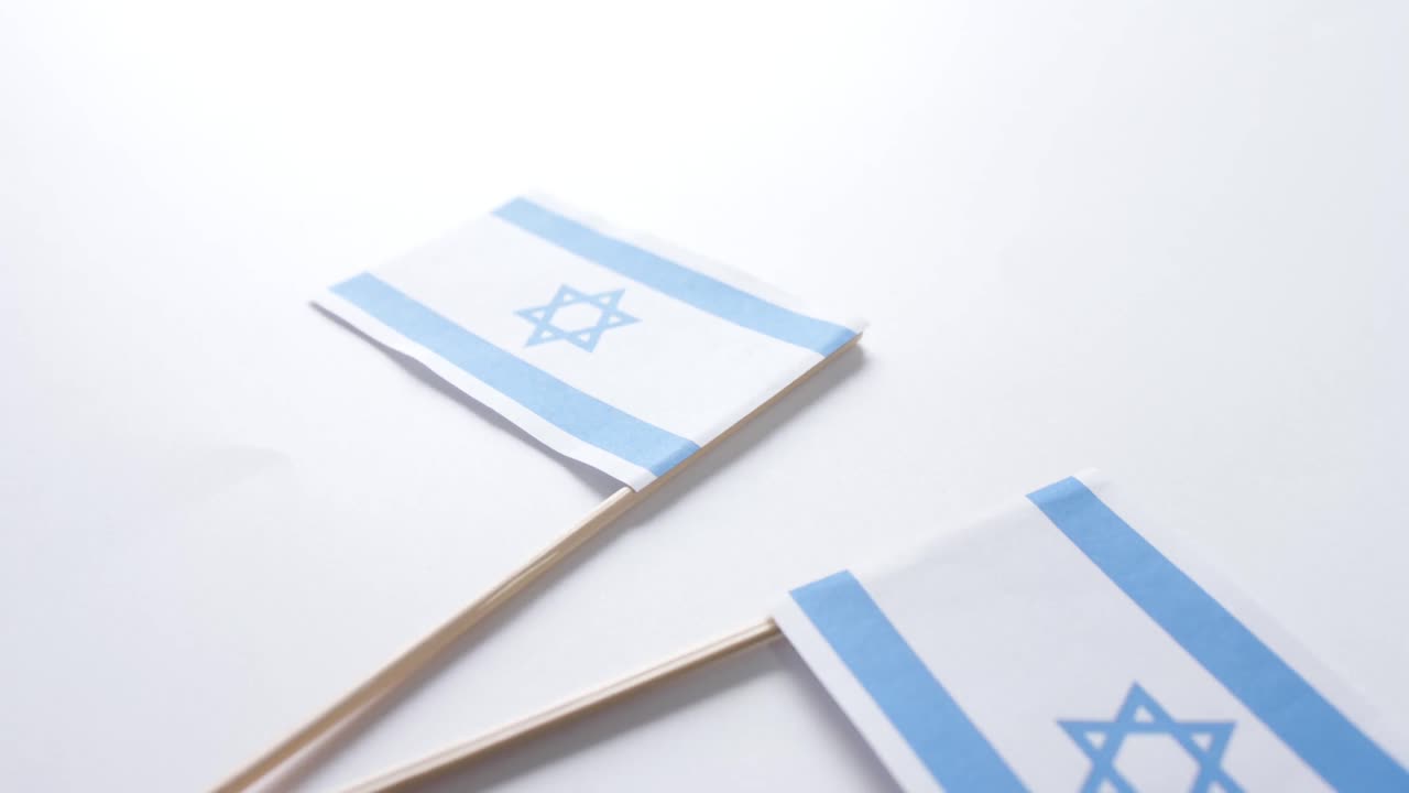 Primo piano di due bandiere di Israele adagiate su sfondo bianco.
