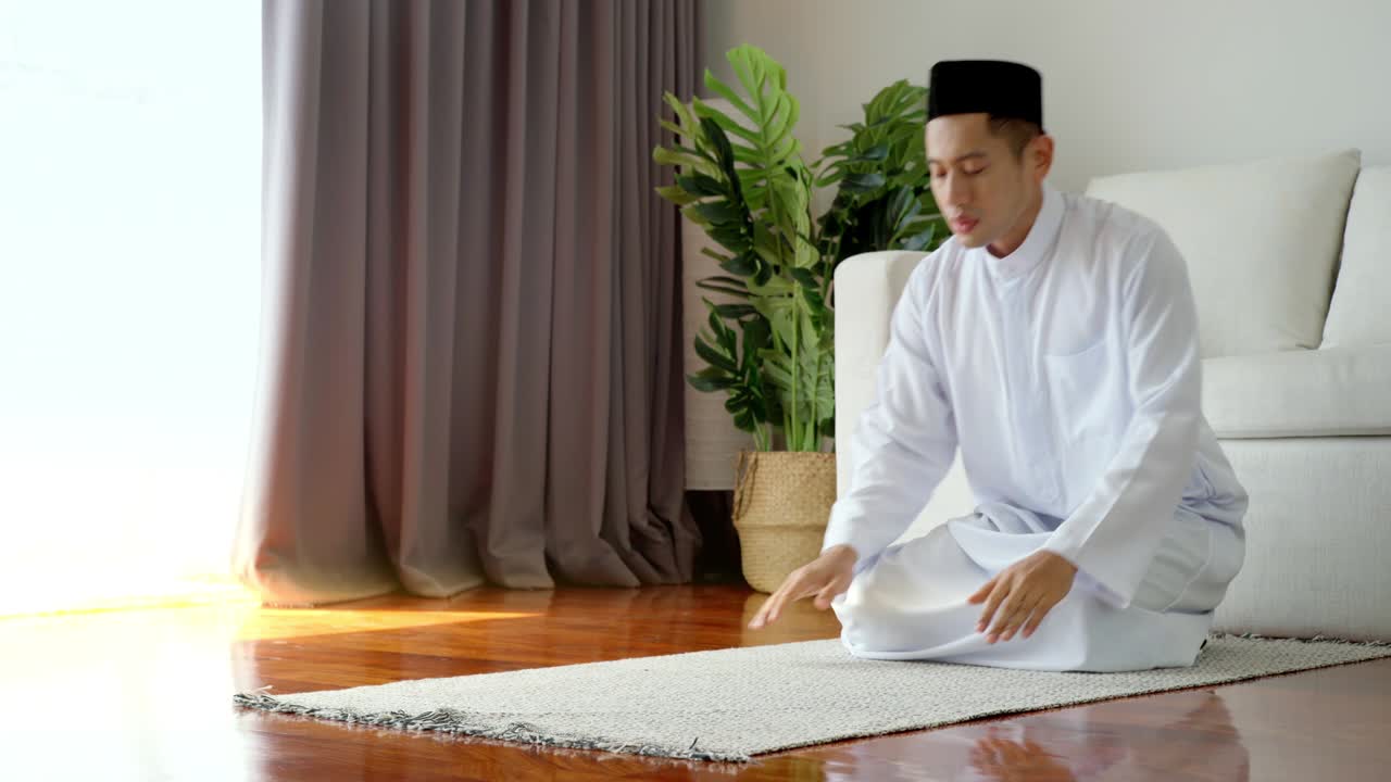 아시아의 무슬림 남자가 집에서 기도하고 드리고 있습니다.