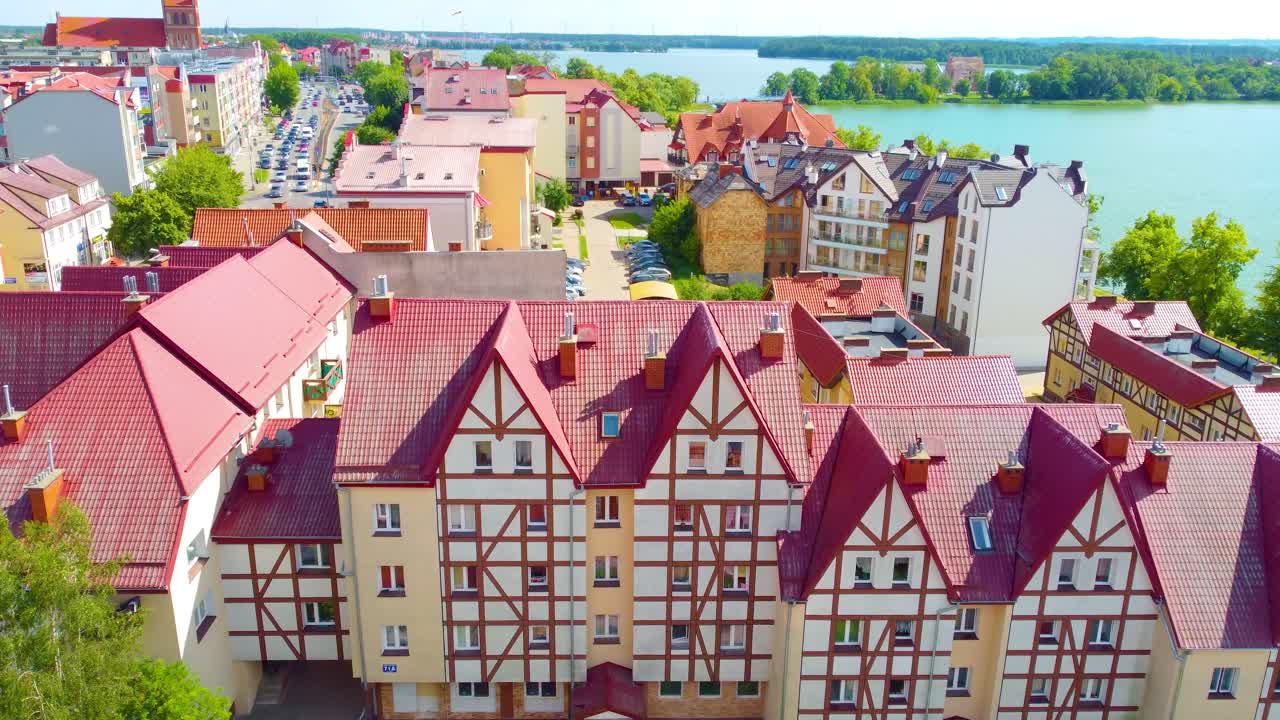 Aerial view of beautifully architected building with red roof, vibrant garden in front shines in sunlight in Northern Poland.