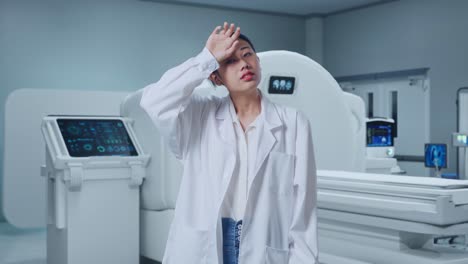 tired asian woman doctor standing with mri machine in the hospital