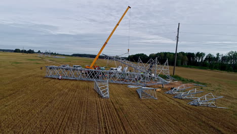 crane and crew erecting a electrical transmission powerline pylon in the european countryside - orbiting aerial view