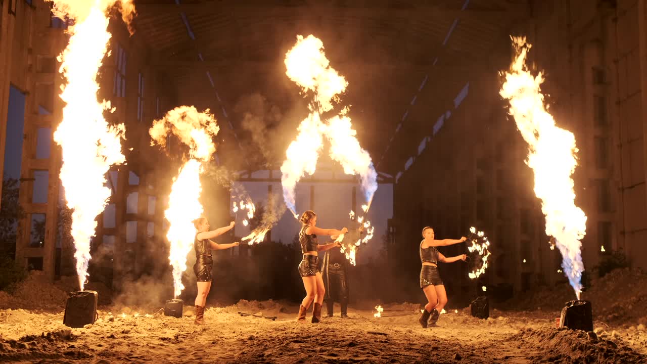 un grupo de artistas profesionales con fuego muestran el espectáculo haciendo malabarismos y bailando con fuego en cámara lenta.