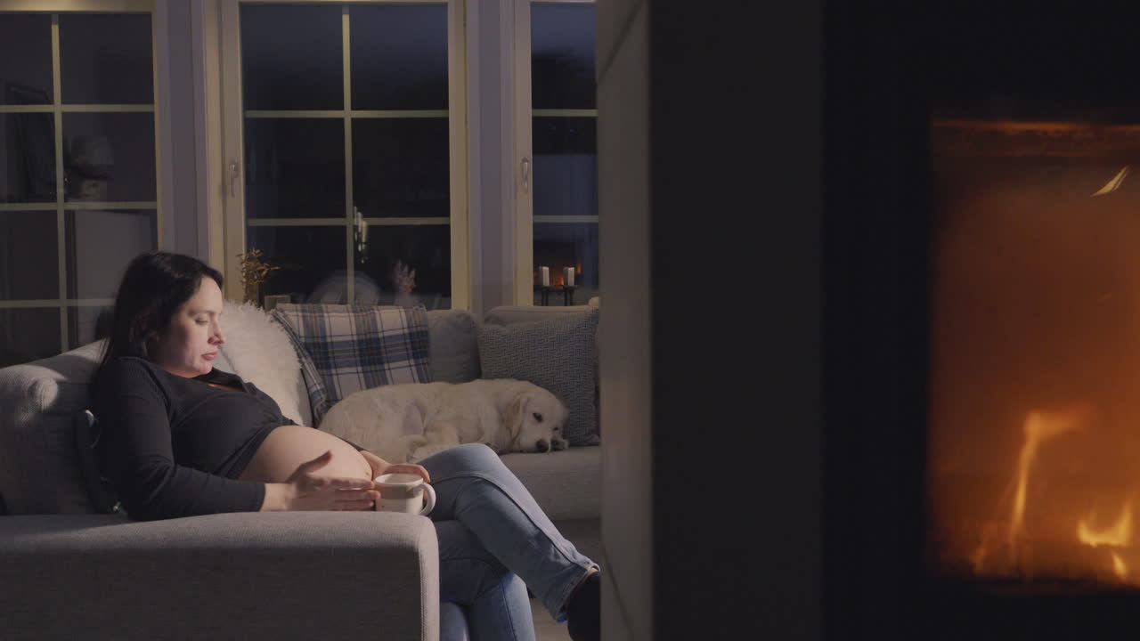 임신 중인 여성이 골든 리트리버와 함께 소파에 앉아 있습니다.