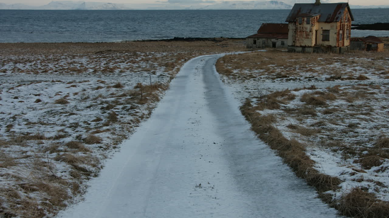 버려진 농경지로 이어지는 얼어붙은 시골 도로의 평온한 겨울 풍경 - 아이슬란드, 4k