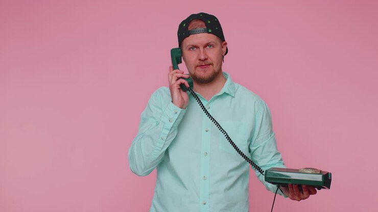 Cheerful tourist man secretary talking on wired vintage telephone of 80s, says hey you call me back