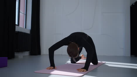 woman doing yoga on a mat in a studio