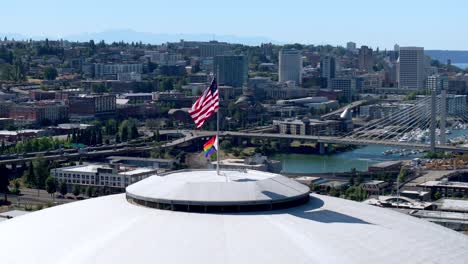american and pride flags on tacoma dome with east 21st street bridge in the background in washington, usa. - aerial shot