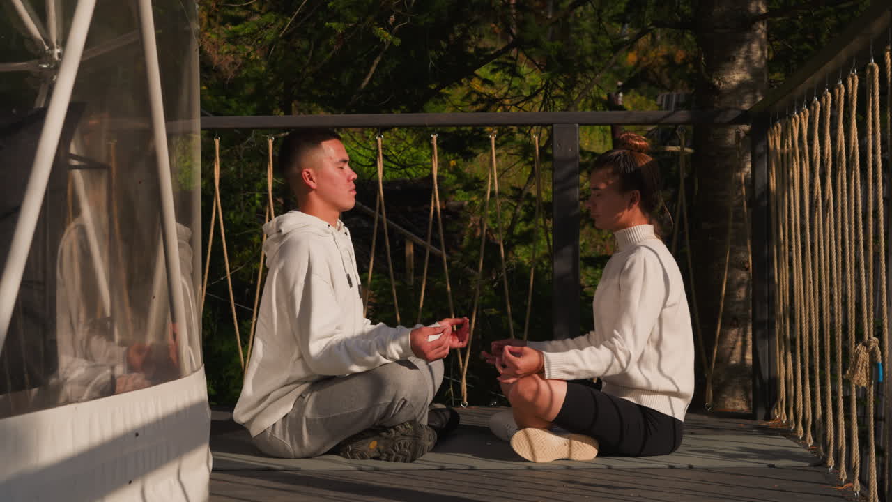 Couple practices meditation at glamping. Young man and woman work upon relationship problems with yoga techniques at eco resort retreat. Partners vacation