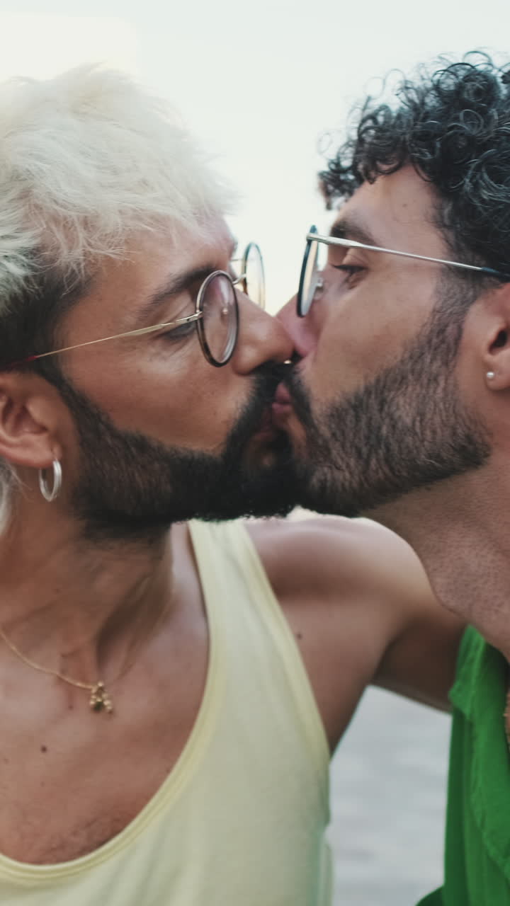 Pareja gay feliz compartiendo un beso y conversando al aire libre