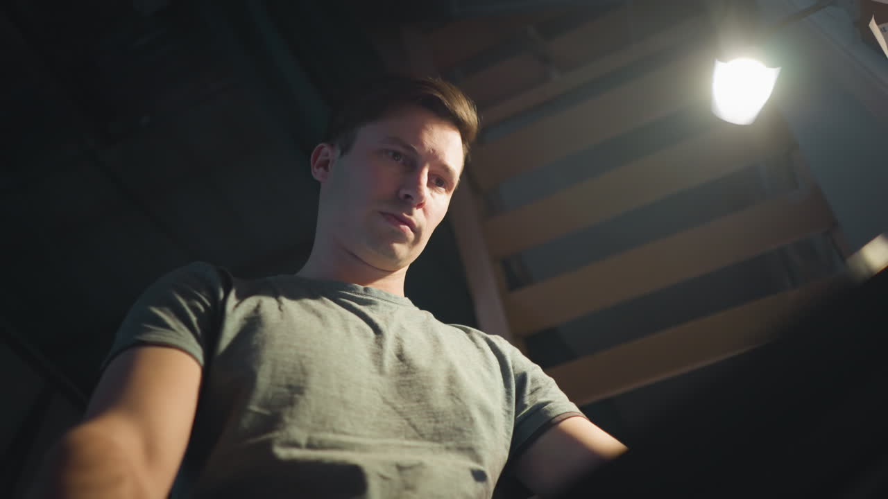 Person focusing on adjusting equipment, interacting with digital panel, engaged in technical tasks, working in a studio setting with lighting and tools visible in the background