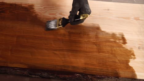 applying wood stain to a plank