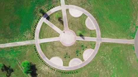 top view of a bicycle woman riding a bicycle on a circular road in a city park.