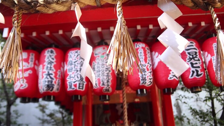 Traditionelle røde lanterner og hellige dekorationer ved Nishiki Tenmangu-helligdommen ved siden af Nishiki-markedet i Kyoto, Japan, der fremhæver den spirituelle atmosfære på dette historiske shinto-sted