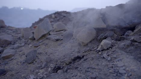 coal mine with smoke and burning embers coming from the underground coal field fire, jharia, jharkhand