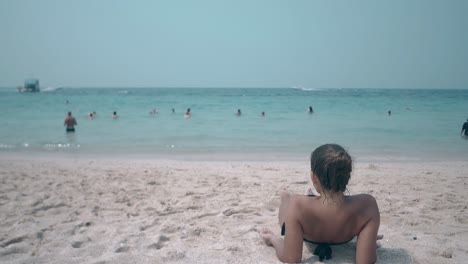 exciting-lady-sunbathes-on-yellow-sand-beach-lit-by-sun